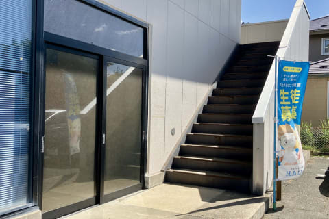 建物右横の階段を上がってください。廊下を進み、つきあたりの向かって左手にあるドアが入口です。