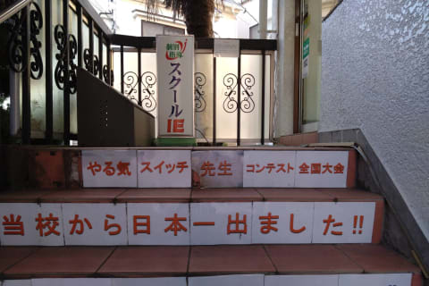 建物の左側にある階段を上って2階へお越しください。