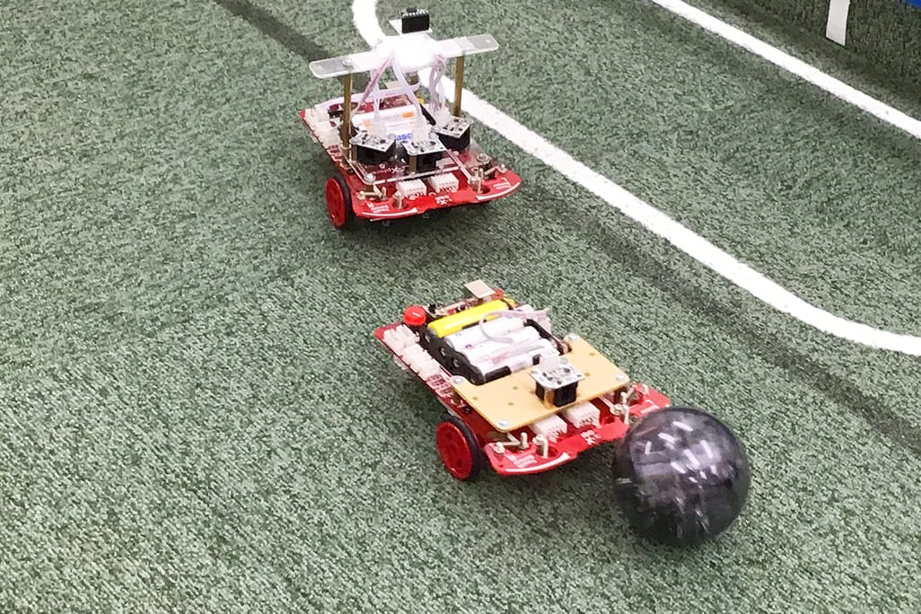 自分で作ったサッカーロボットで他の生徒と対決！センサーでボールを認識し、相手のゴールに向けて動かせるようにプログラミングします。相手の動きを見ながら調整できるかもポイント。【2024年4月撮影】