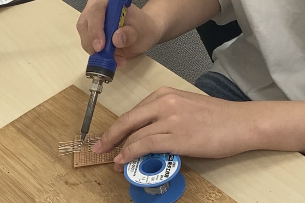 「はんだごて」を使った部品の接着、火傷をしないように細心の注意を払って作業が進みます。【2023年6月撮影】