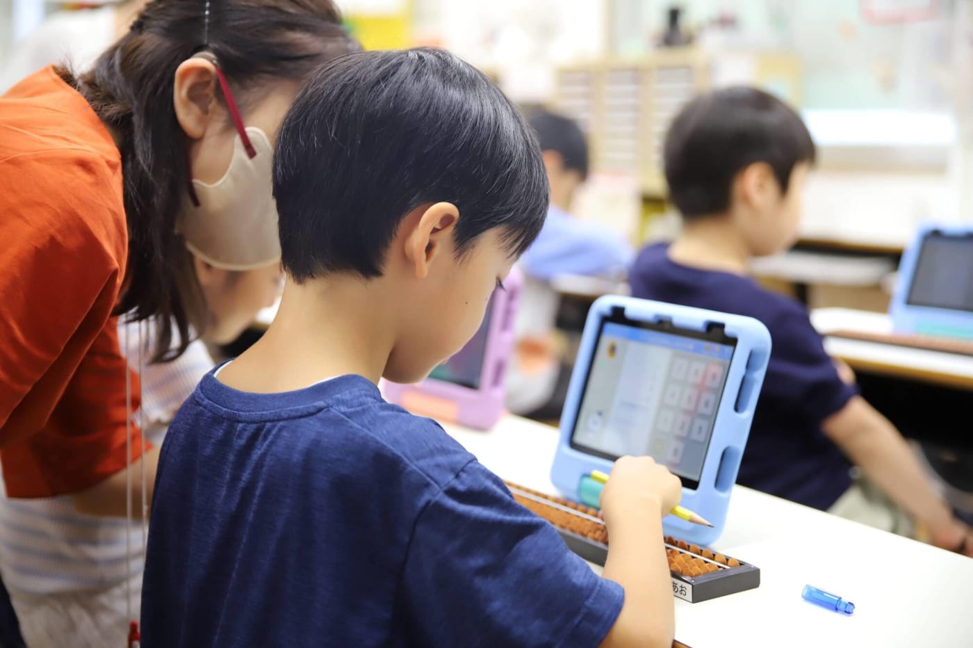 タブレットとそろばんで学ぶ男の子の写真