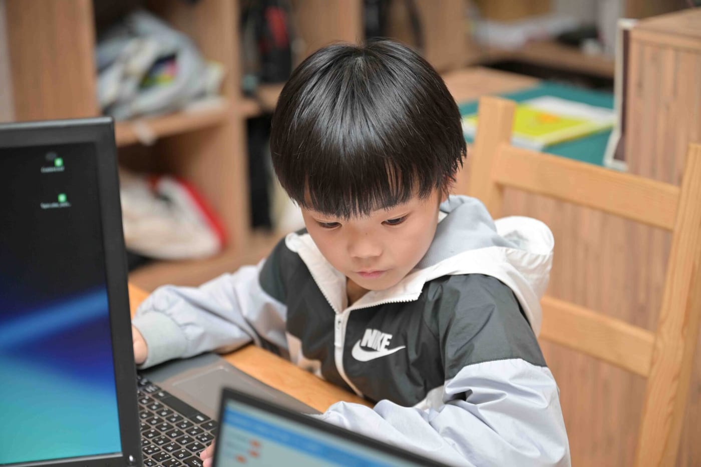 テキストを見ながらプログラミングをする男の子