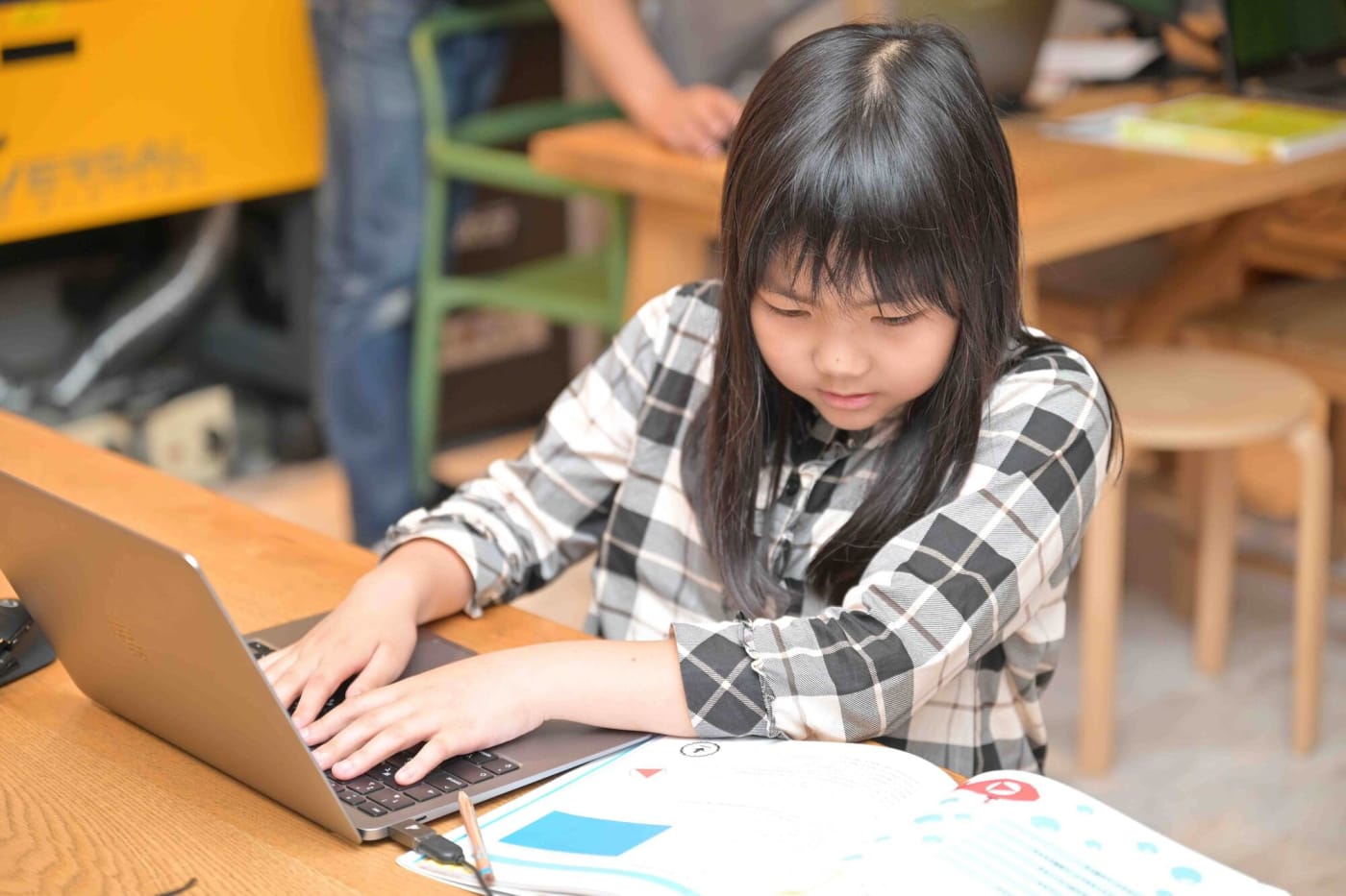 テキストを見ながらプログラミングをする女の子