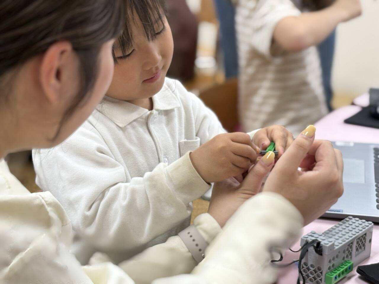 レゴブロックでロボットを作る、先生と子どもの共同作業