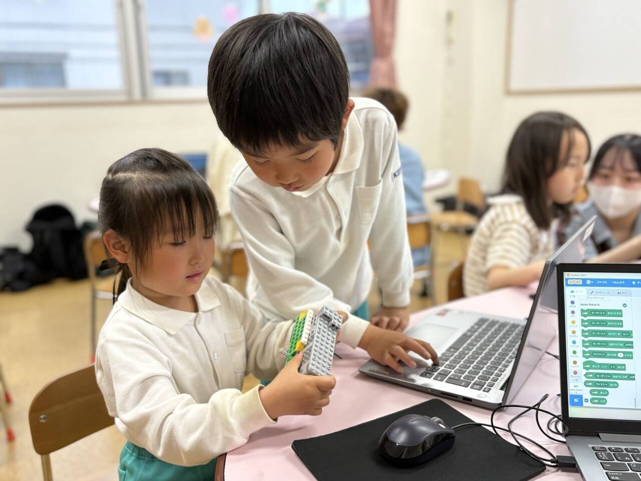 年少の女の子がロボットプログラミングに挑戦、助けてあげるお兄ちゃん。