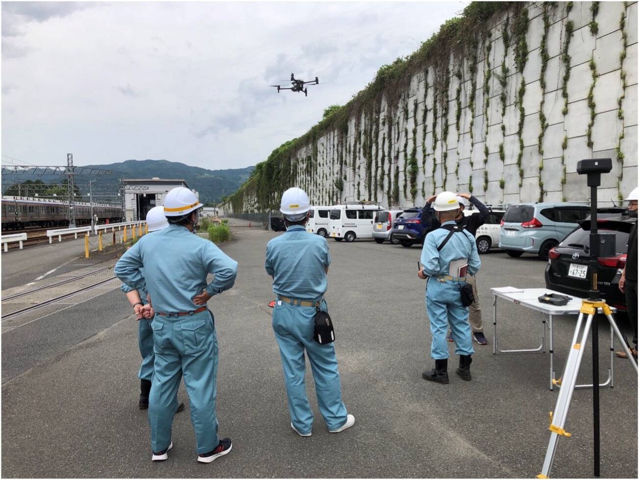 鉄道施設にて、作業着姿でドローンを飛行させる様子