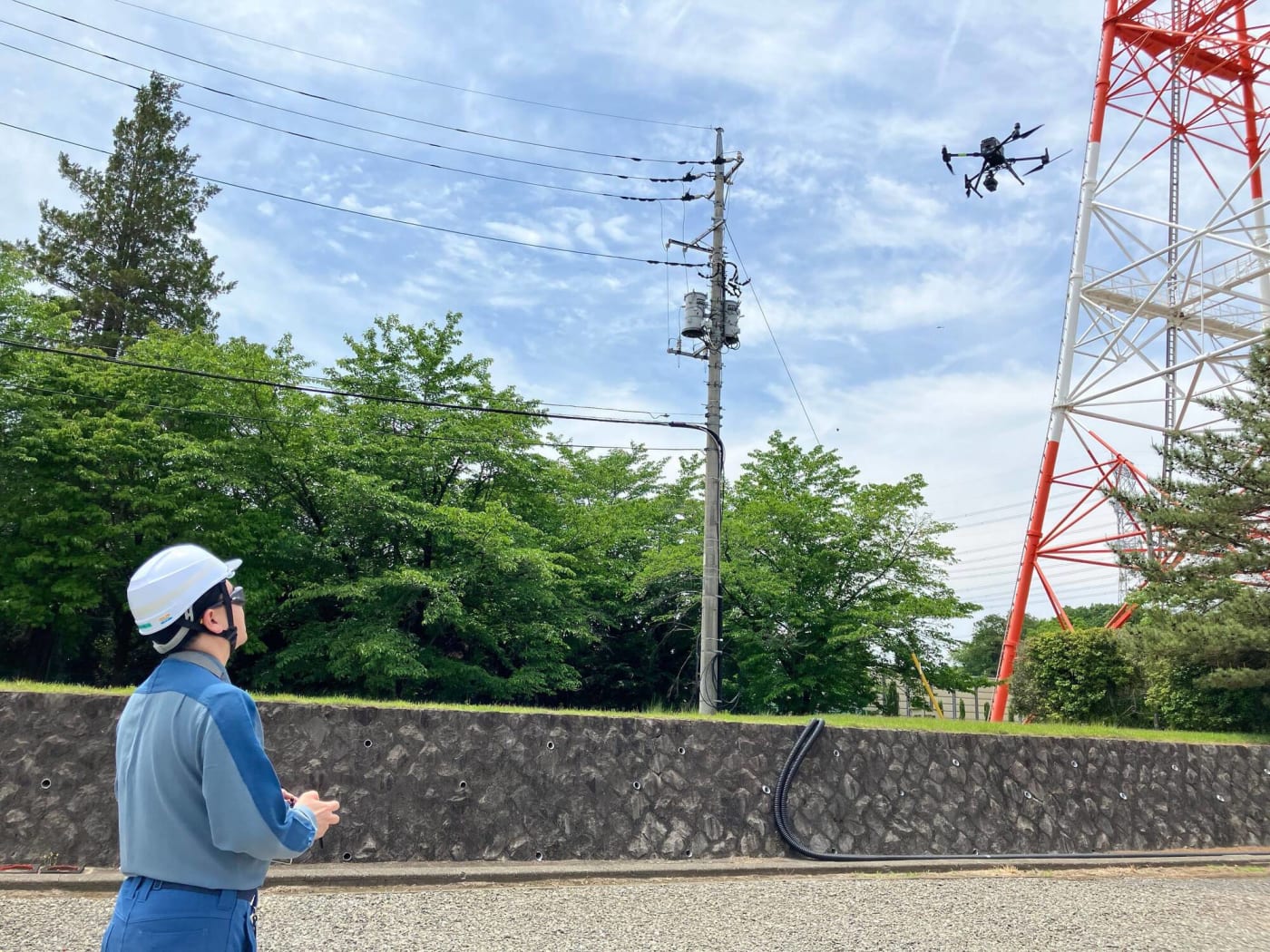 電力インフラ設備の点検にドローンを操縦する男性