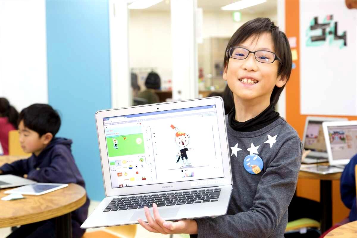 メガネをかけた少年がmacbookairを持っています