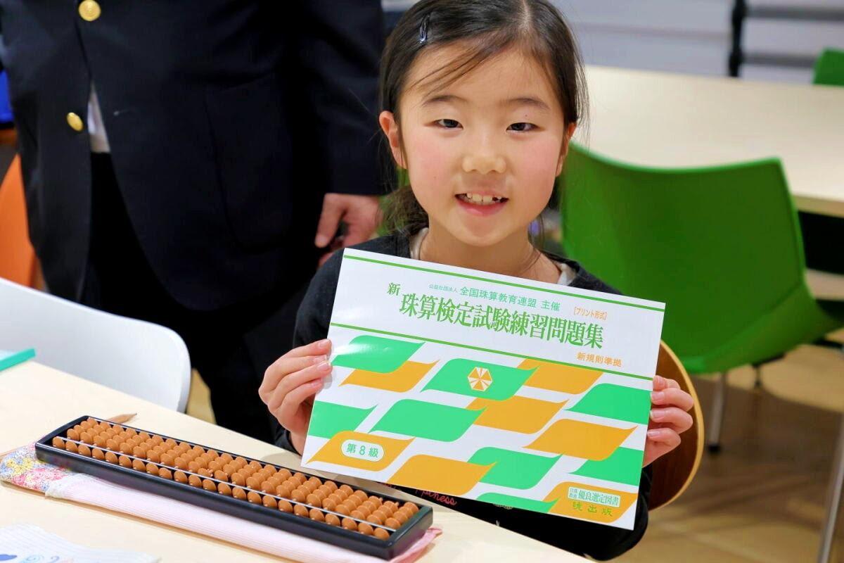 算盤の横にある本を持っている女の子