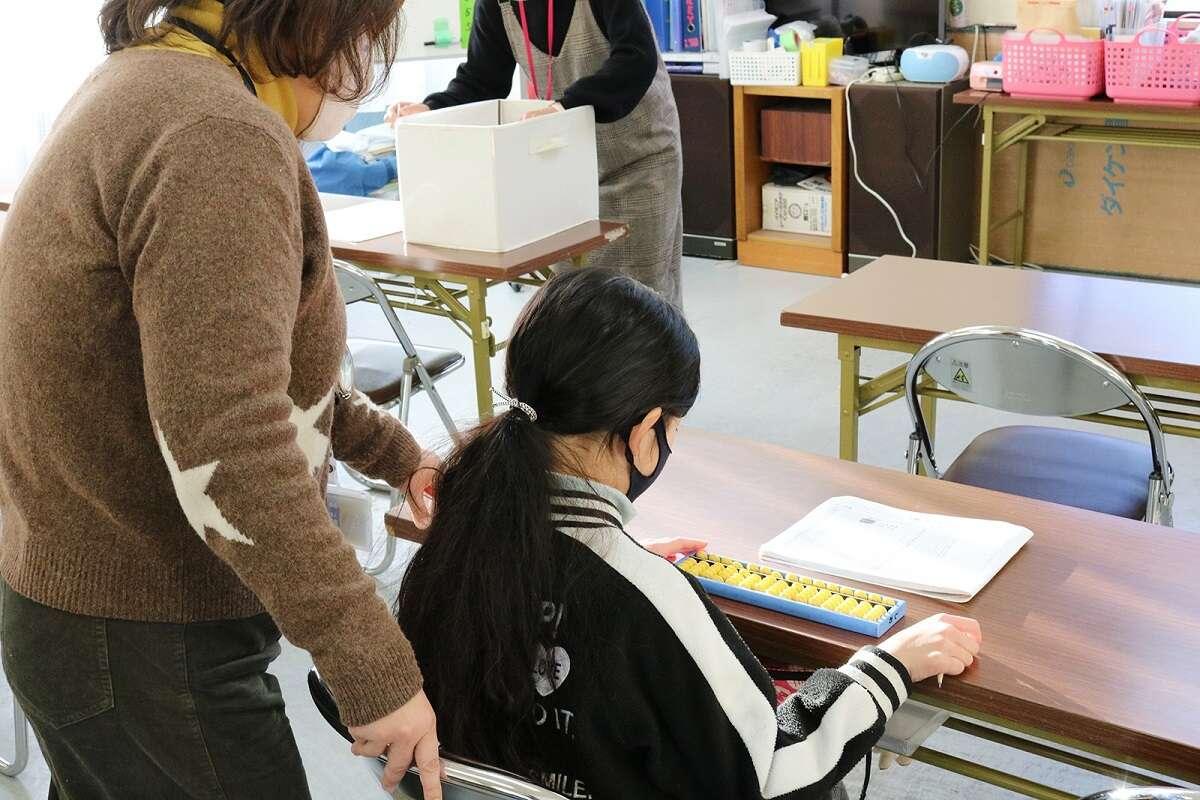 テーブルの上に座っている女の子の隣に立っている女性