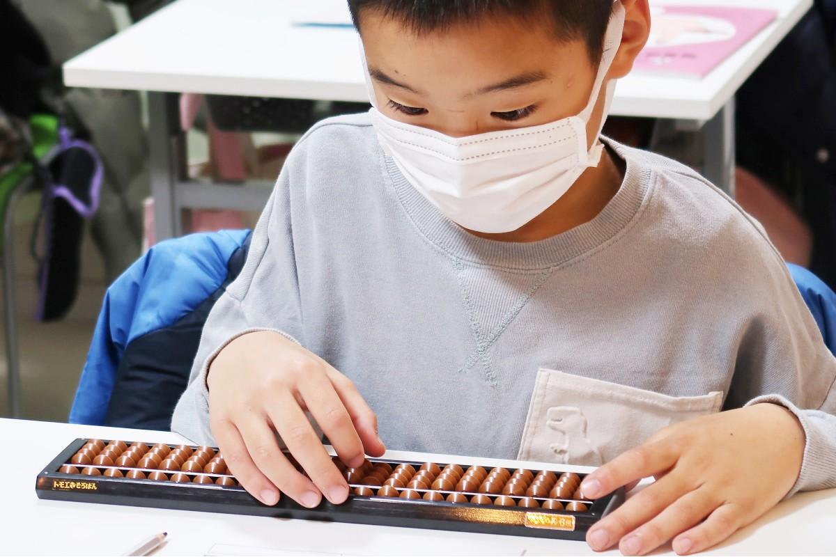 算盤を使用しているマスクをかけた少年