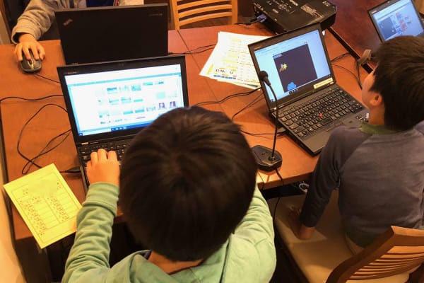 小学生がグループでプログラミングレッスンを受けている様子