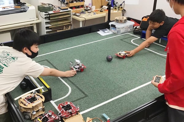 小学校高学年～中学生向けコースでは、自作ロボットを使ってサッカー競技に挑戦。 生徒同士や見本ロボットとの対戦で課題を見つけ、加工やプログラムの改善を重ねながら、動きの精度を高めていきます。【4月撮影】