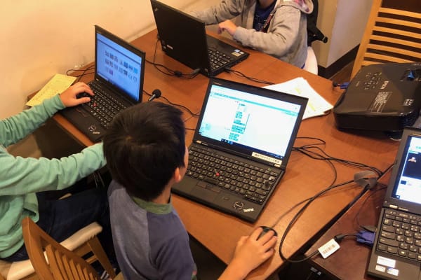小学生がグループでプログラミングレッスンを受けている様子
