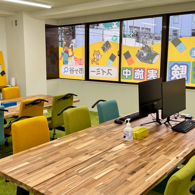 広々とした教室で、集中してプログラミングを学べる環境です！カラフルな椅子と自然な木目のテーブルで楽しく快適に学習に取り組めます。