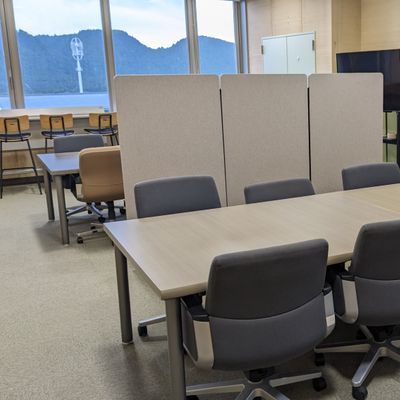 プログラミング教育「HALLO」あいコムこうか土山校のレッスンルームです。大きなモニターに余裕のある座席配置が特徴です。奥には保護者さま待機場所がございます。