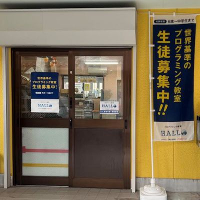 入口のポスターと、HALLOのノボリが目印です。入口は鍵がかかっていることが多いので、インターホンにてお知らせください。