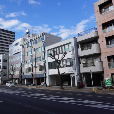 手前の道路が石田街道で、左奥にまっすぐ進むと静岡駅に着きます。壁面に「WinBe」「HALLO」の看板がついた建物の3階です。