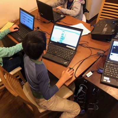 小学生がグループでプログラミングレッスンを受けている様子