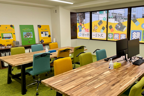 広々とした教室で、集中してプログラミングを学べる環境です！カラフルな椅子と自然な木目のテーブルで楽しく快適に学習に取り組めます。