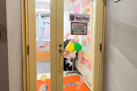 エレベーターか階段で2階にお上がりいただくと、黄色いガラス扉がございます。こちらが当校の入口です。