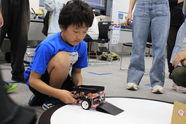 Robo RAVE での大会の様子。こちらのロボットは、手前に坂を作ることで、相手のロボットの車輪を乗り上げさせて持ち上げやすくする工夫をしています。【2023年10月撮影】