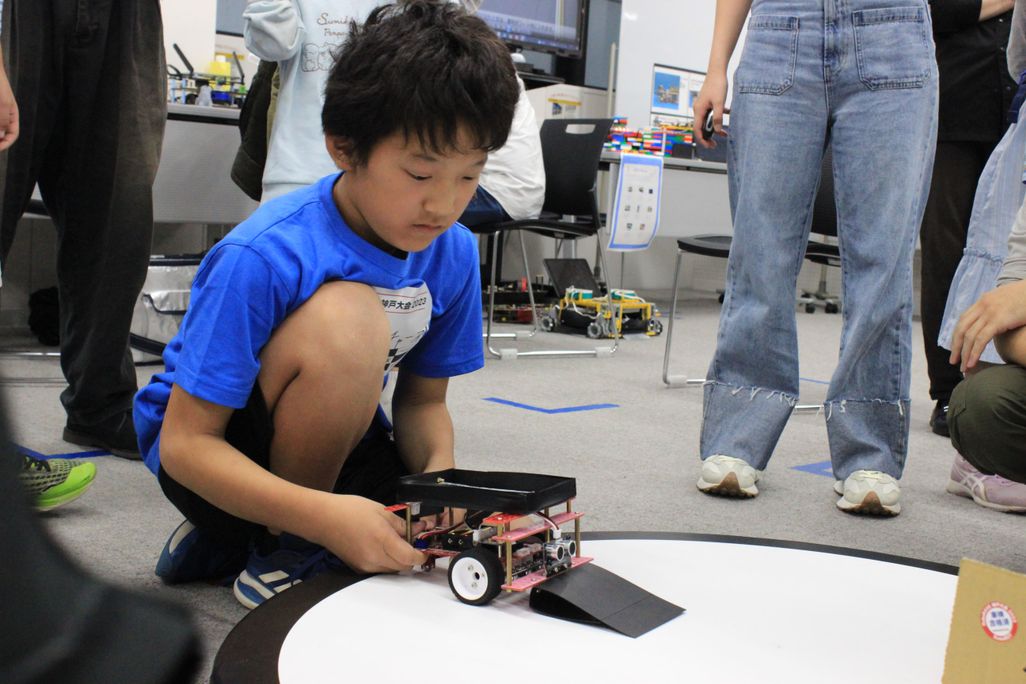 Robo RAVE での大会の様子。こちらのロボットは、手前に坂を作ることで、相手のロボットの車輪を乗り上げさせて持ち上げやすくする工夫をしています。【2023年10月撮影】