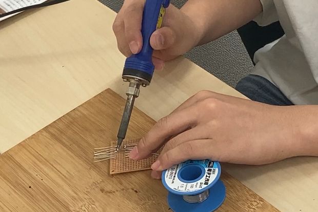 「はんだごて」を使った部品の接着、火傷をしないように細心の注意を払って作業が進みます。【2023年6月撮影】