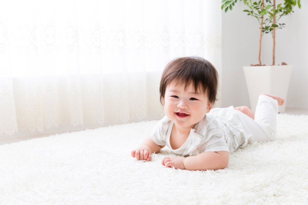 白いカーペットの上に横たわっている赤ちゃん
