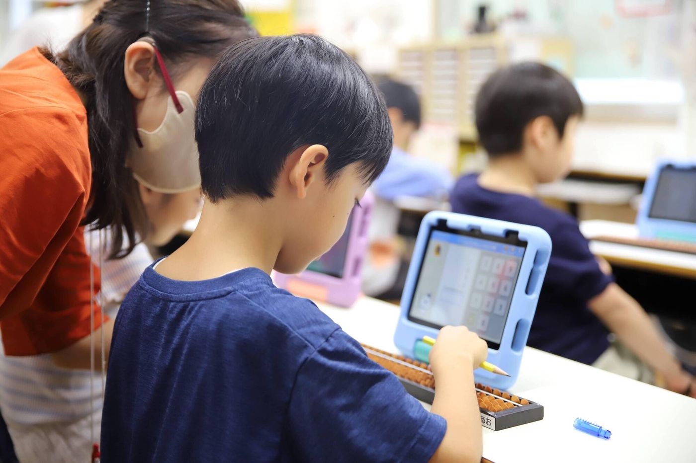 タブレットとそろばんで学ぶ男の子の写真