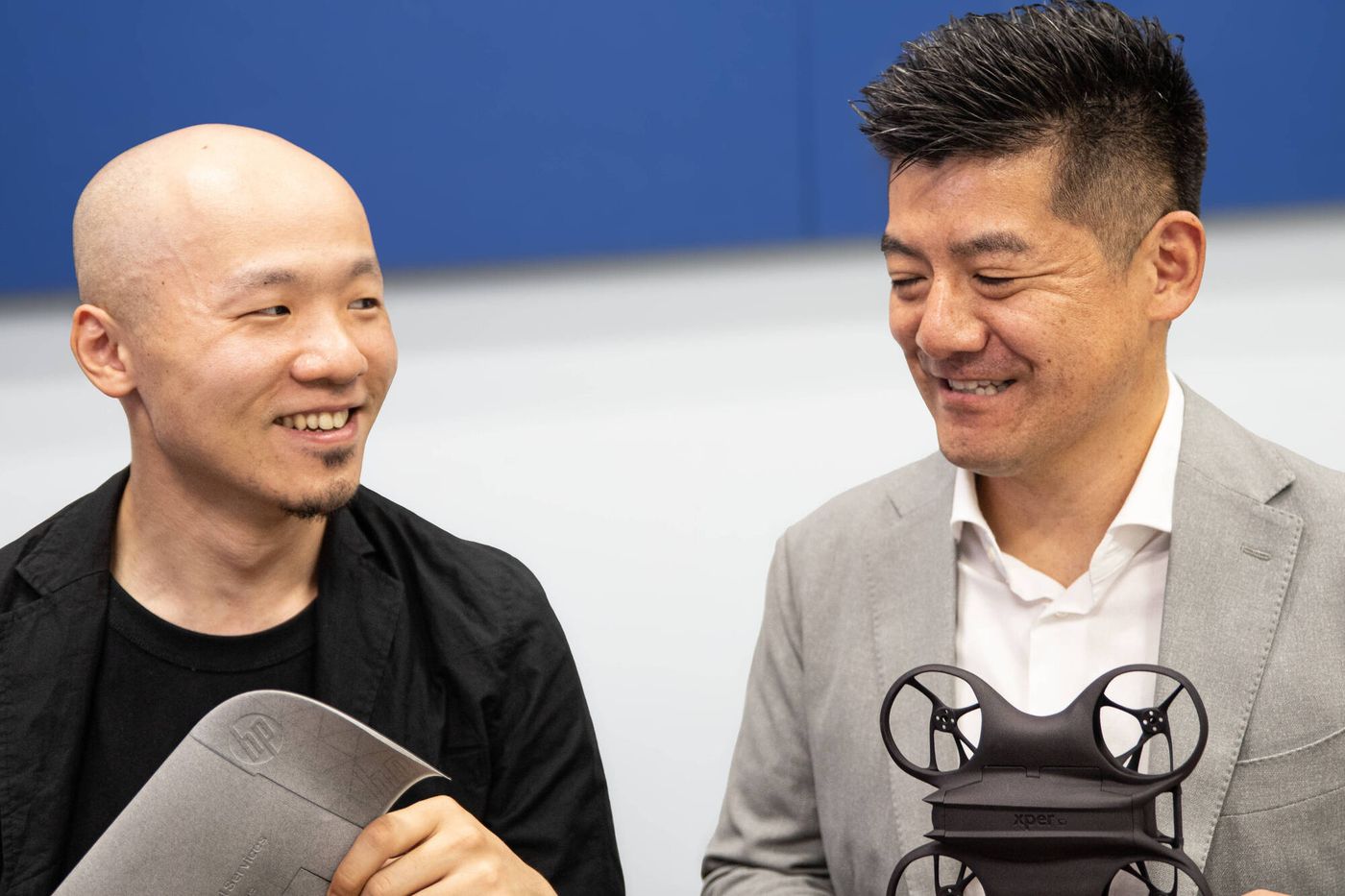 3Dプリンターで作られたパーツを手に語る宮内氏と深見氏