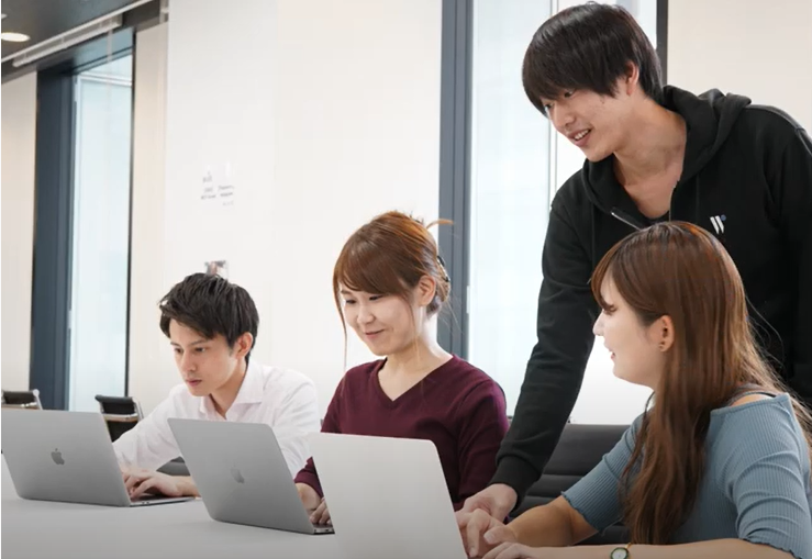 男性更新が3名の生徒に対してプログラミングを教えている