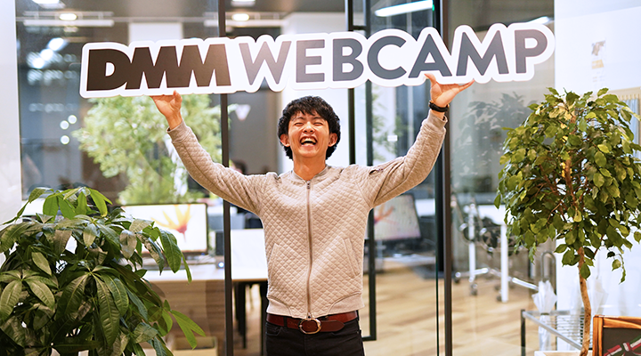 SHIFT TERAS CAMPUS（旧DMM WEBCAMP)のボードを上に掲げて喜んでいる男性が立っている