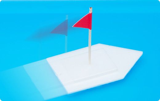 赤い旗が付いた小さな白いボートが水面を進んでいる