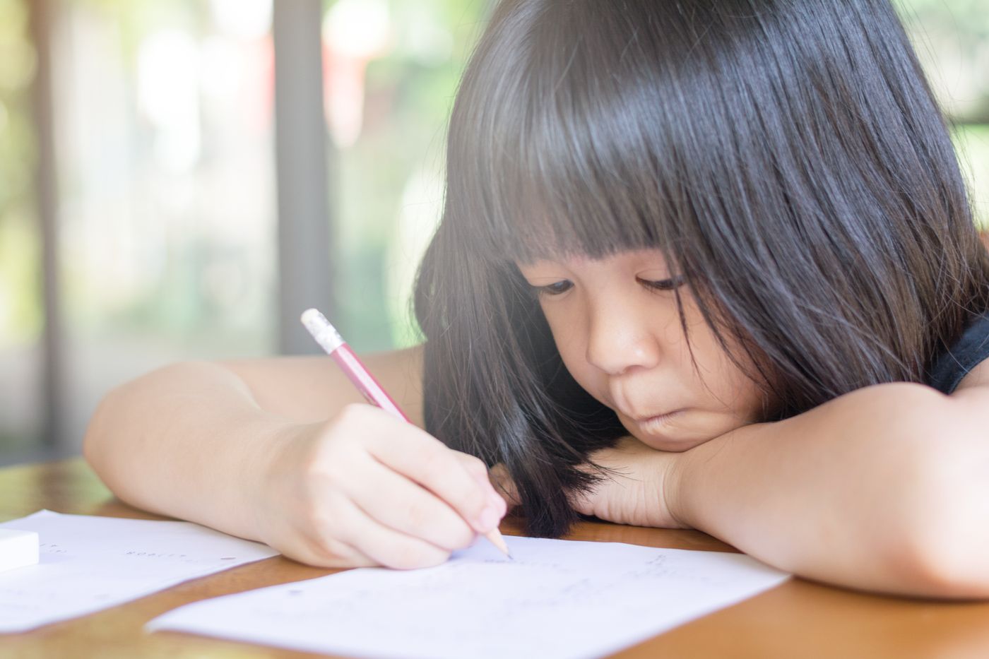 鉛筆で紙に書いている少女