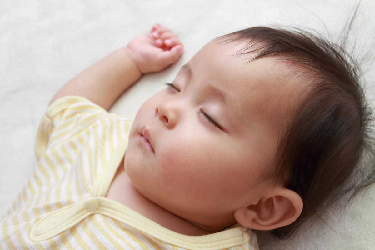 黄色と白のストライプのシャツを着た赤ちゃんが寝ています