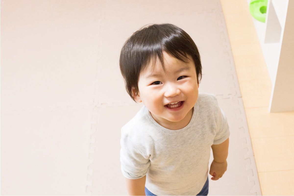 白いtシャツを着た小さな男の子がカメラに微笑んでいます