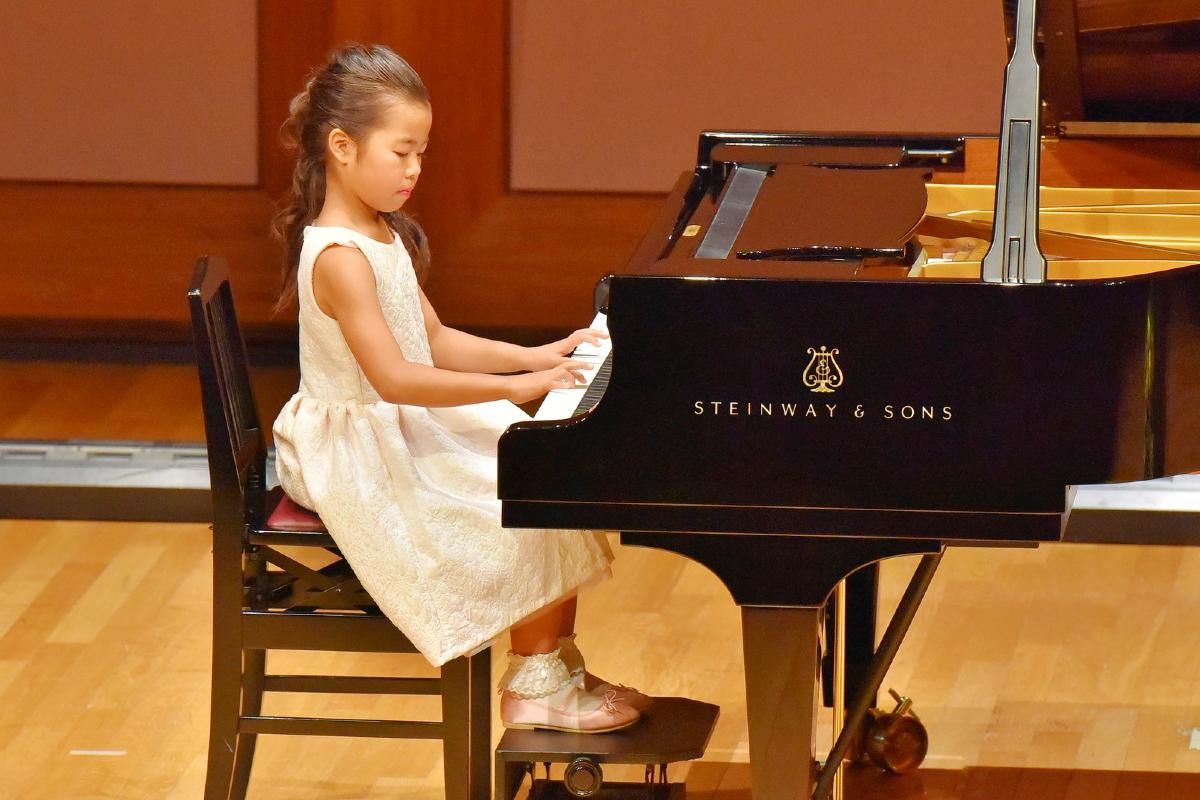 小さな女の子がsteinway&sonsのピアノの前に座っています