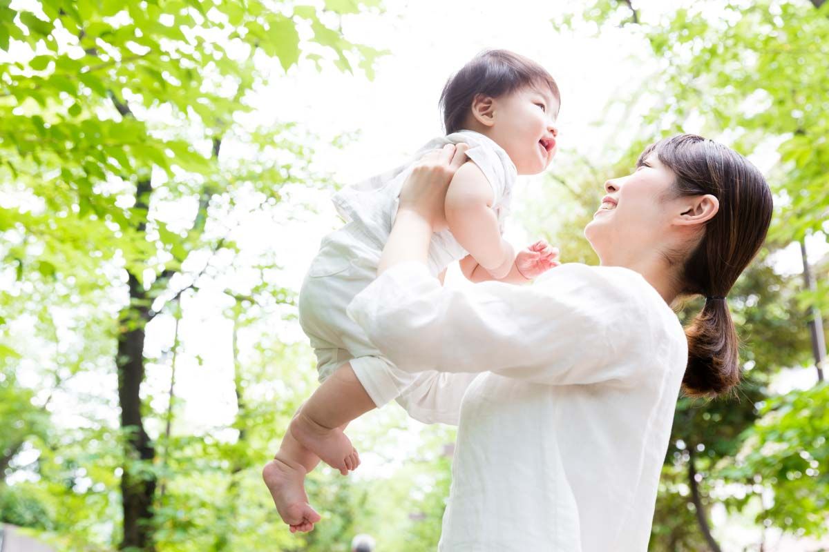 赤ちゃんを空中に持ち上げている女性