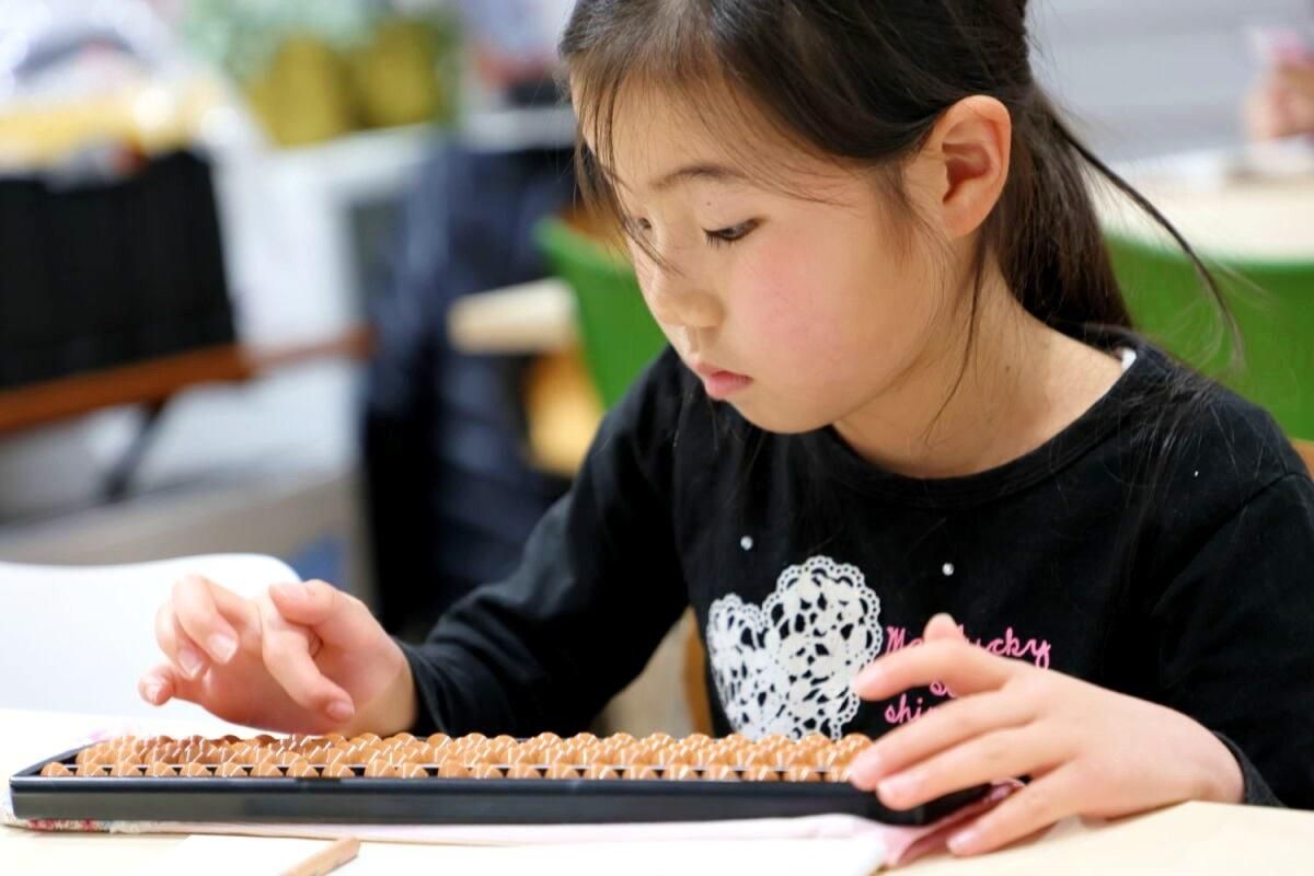 黒いシャツを着た少女が算盤を使用しています