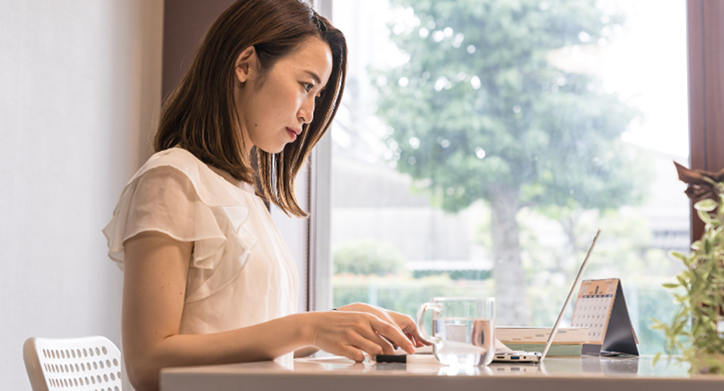 女性が机位に座ってPCを見つめており、真剣に勉強している姿