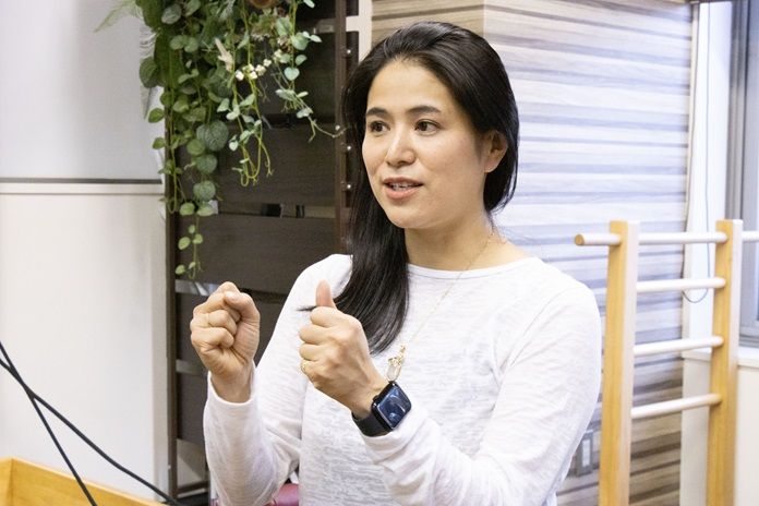 白いシャツを着た女性が腕に黒い時計をつけている