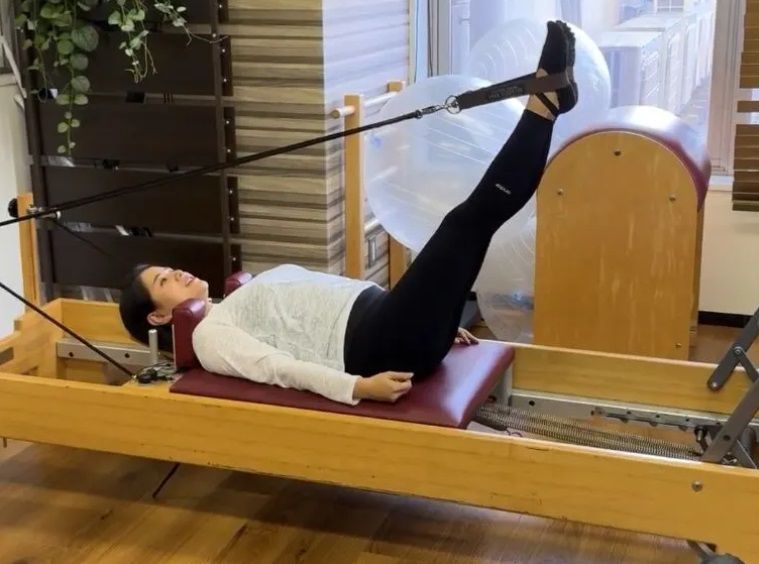 女性がピラティスマシンの上に横たわっています