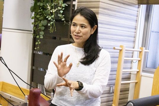 白いシャツを着た女性が部屋に立っています。