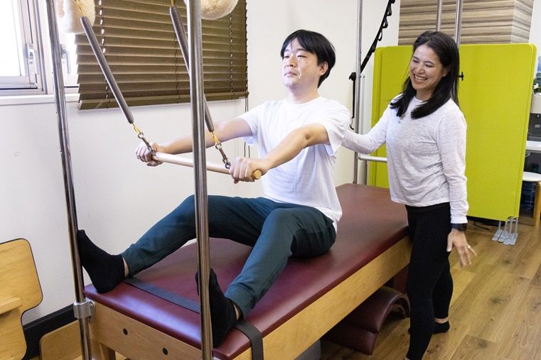 女性が男性にピラティスを教えている