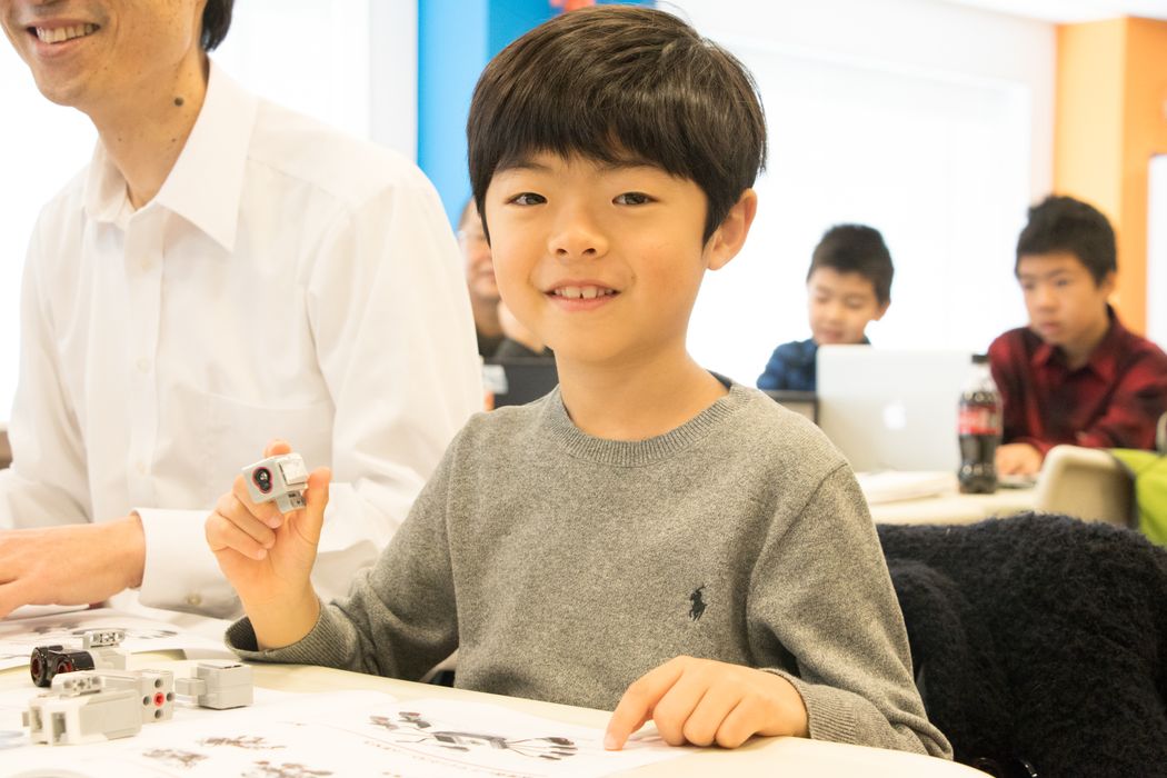 グレーのセーターを着た少年がテーブルに座っている