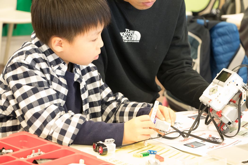 ノースフェイスのシャツを着た男の子がロボットを作っている