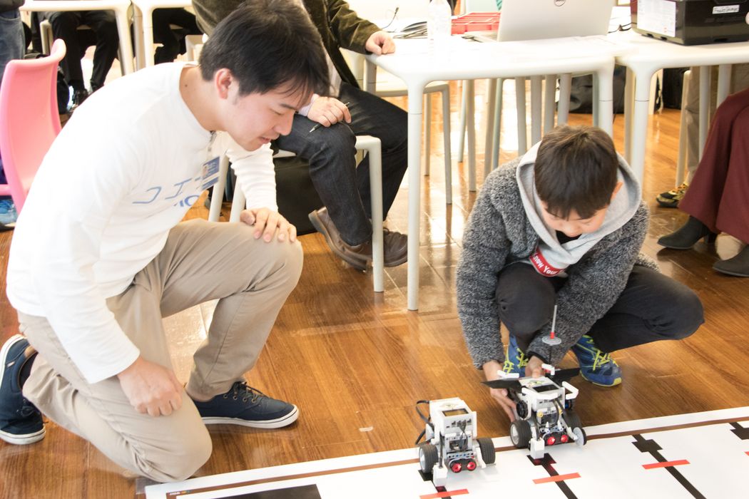 白いシャツを着た男性がロボットを見ています
