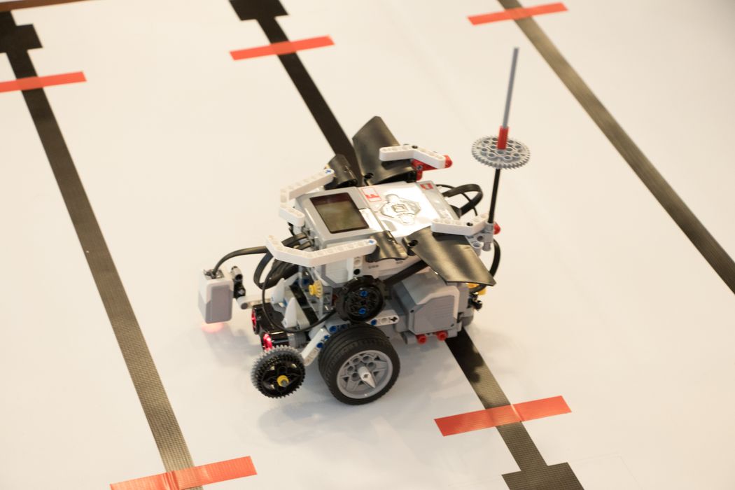 黒いテープで囲まれた白いトラックの上を走っているロボット